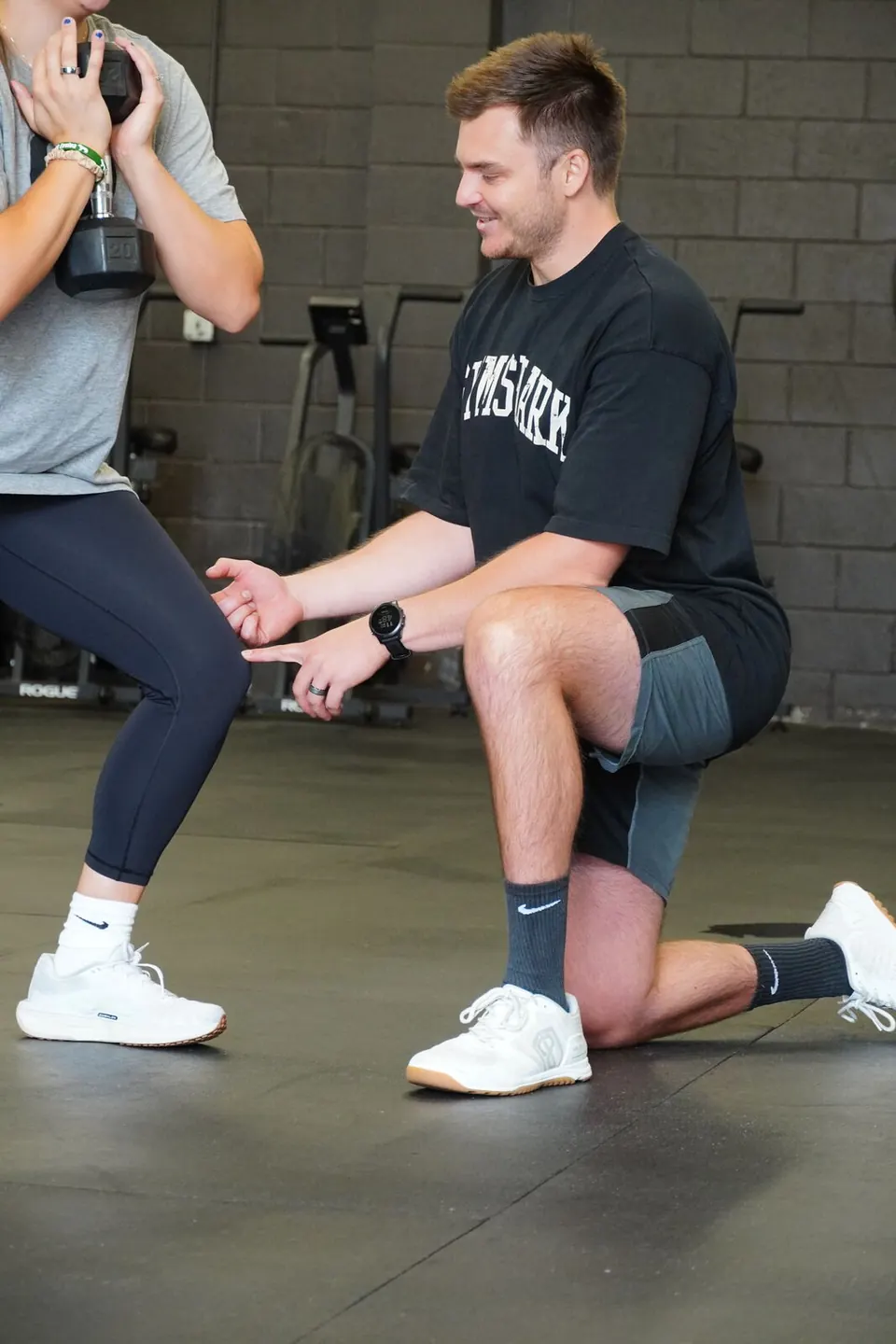 Coach kneeling beside a client to cue her lunge during a personal training session